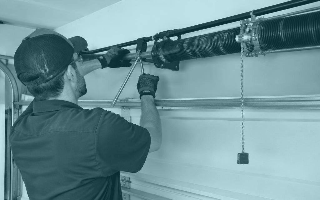 Technician servicing a residential garage door spring
